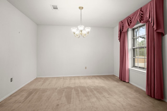 empty room with light carpet and a notable chandelier