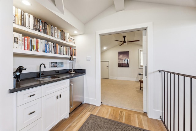 interior space featuring sink, white cabinetry, vaulted ceiling, light wood-type flooring, and fridge