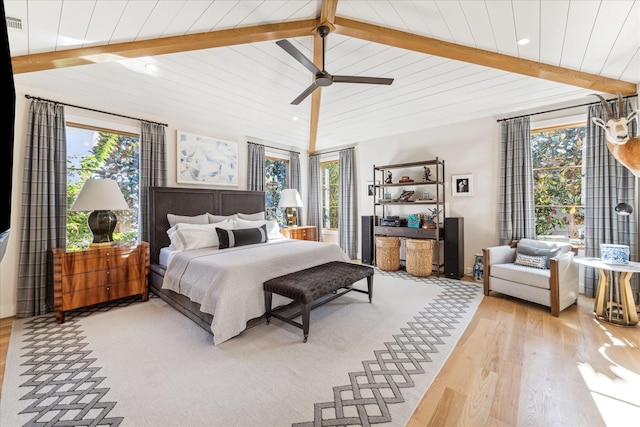 bedroom featuring multiple windows, vaulted ceiling with beams, and light hardwood / wood-style flooring