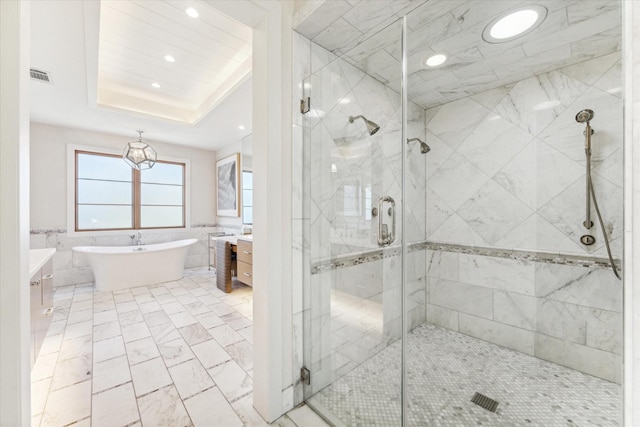 bathroom featuring vanity, separate shower and tub, a raised ceiling, and tile walls