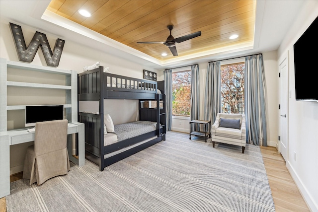 unfurnished bedroom with wood ceiling, wood-type flooring, a tray ceiling, and built in desk