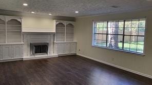 unfurnished living room featuring dark hardwood / wood-style floors and a textured ceiling