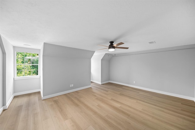 additional living space with ceiling fan, lofted ceiling, a textured ceiling, and light wood-type flooring