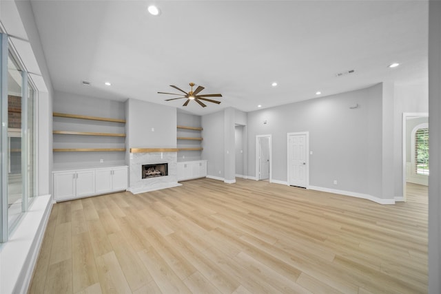 unfurnished living room with ceiling fan, a high end fireplace, and light hardwood / wood-style flooring