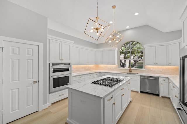 kitchen featuring appliances with stainless steel finishes, a center island, sink, and white cabinets