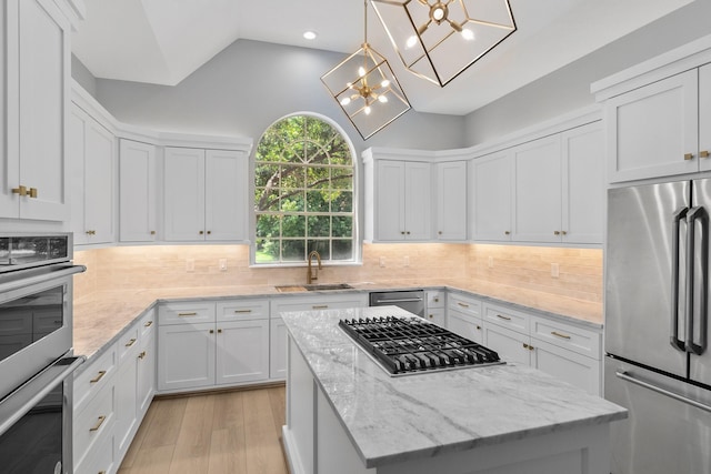 kitchen featuring a kitchen island, sink, white cabinets, hanging light fixtures, and stainless steel appliances