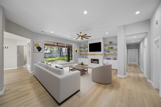 living room featuring ceiling fan, light hardwood / wood-style flooring, and built in features