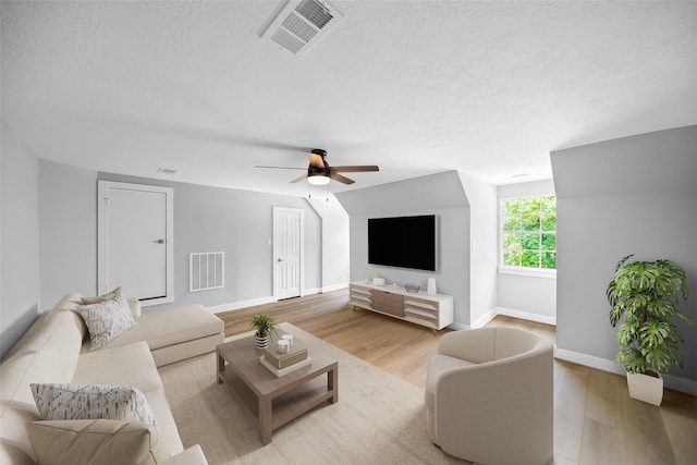 living room with ceiling fan, light hardwood / wood-style floors, and a textured ceiling