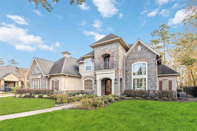 french provincial home with central AC, a front lawn, and a balcony