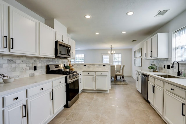 kitchen featuring sink, a notable chandelier, pendant lighting, stainless steel appliances, and white cabinets