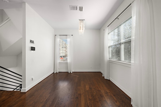 spare room featuring dark hardwood / wood-style floors and a chandelier