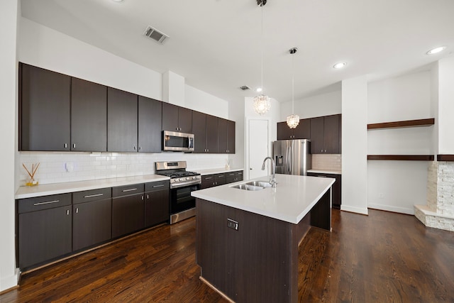 kitchen with sink, decorative light fixtures, dark brown cabinets, an island with sink, and stainless steel appliances