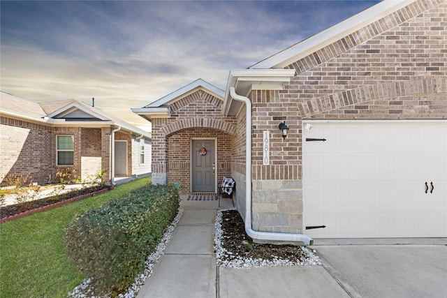 property entrance featuring a garage and brick siding