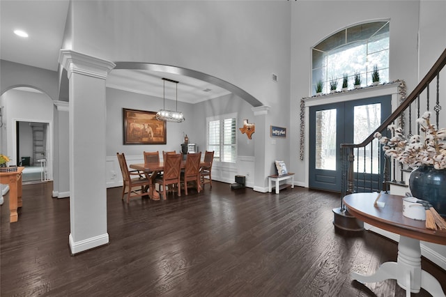 foyer entrance with dark hardwood / wood-style floors, decorative columns, a high ceiling, ornamental molding, and french doors