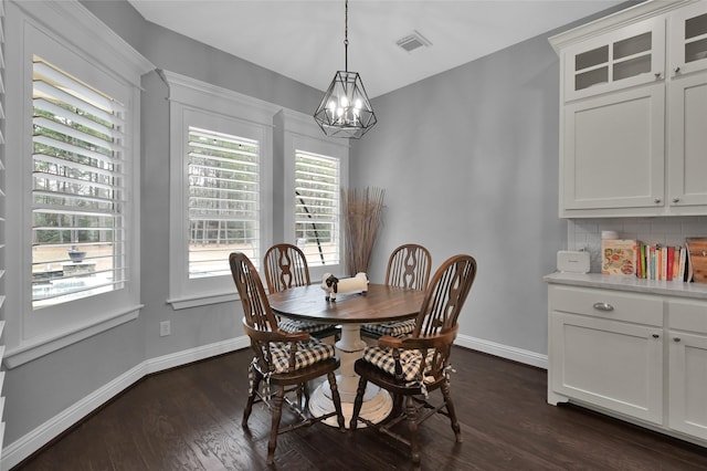 dining area with dark hardwood / wood-style floors and an inviting chandelier