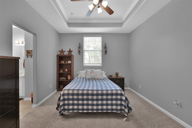 bedroom featuring connected bathroom, light colored carpet, ornamental molding, and a raised ceiling