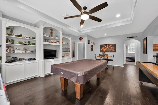 game room with dark wood-type flooring, ornamental molding, a raised ceiling, and ceiling fan