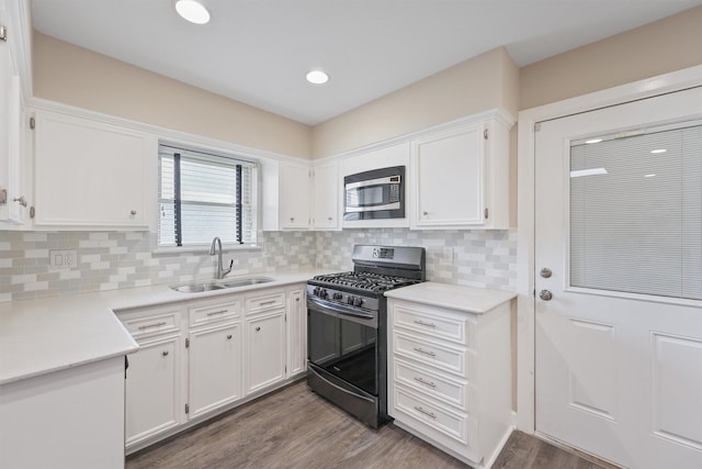 kitchen with hardwood / wood-style flooring, appliances with stainless steel finishes, sink, and white cabinets