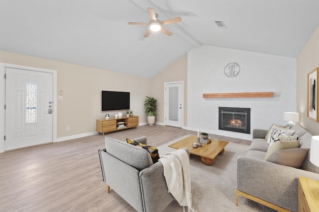 living room featuring ceiling fan, a fireplace, lofted ceiling with beams, and light hardwood / wood-style flooring