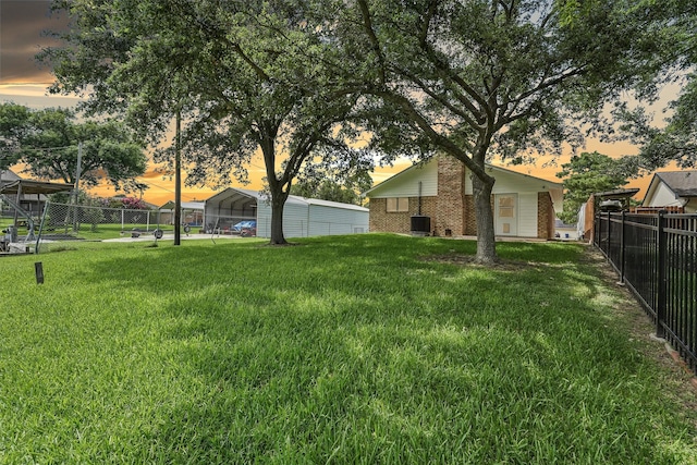 yard at dusk with central AC and a carport