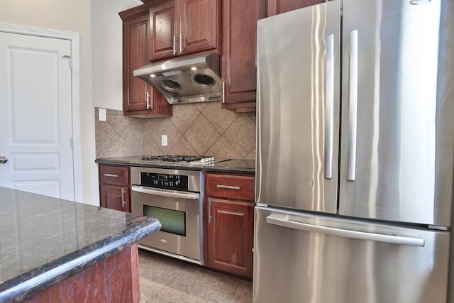 kitchen featuring stainless steel appliances, decorative backsplash, and dark stone counters