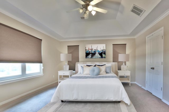 bedroom with light carpet, ceiling fan, and a tray ceiling