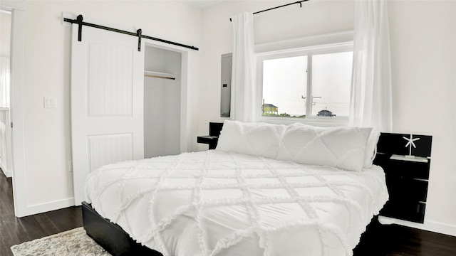 bedroom featuring a barn door, dark wood-type flooring, and a closet