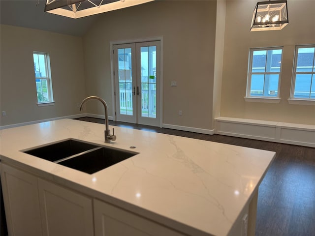 kitchen featuring pendant lighting, sink, white cabinetry, light stone counters, and french doors