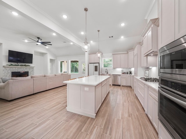 kitchen featuring stainless steel appliances, white cabinetry, a kitchen island, and a stone fireplace