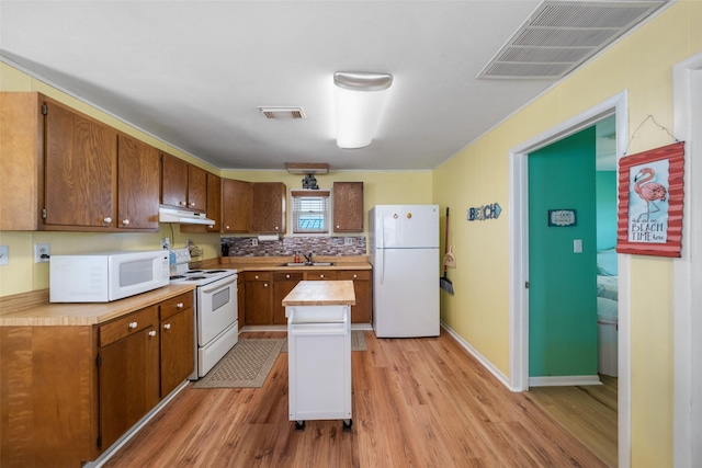 kitchen featuring sink, a center island, white appliances, light hardwood / wood-style floors, and decorative backsplash