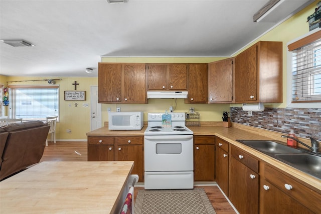 kitchen featuring tasteful backsplash, sink, white appliances, and light hardwood / wood-style flooring