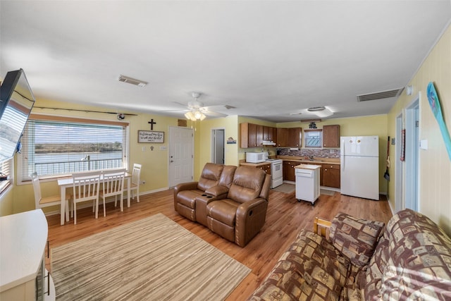 living room with sink, ceiling fan, and light wood-type flooring