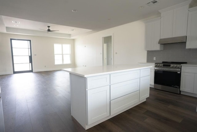 kitchen with stainless steel electric range oven, a kitchen island, white cabinets, decorative backsplash, and a raised ceiling