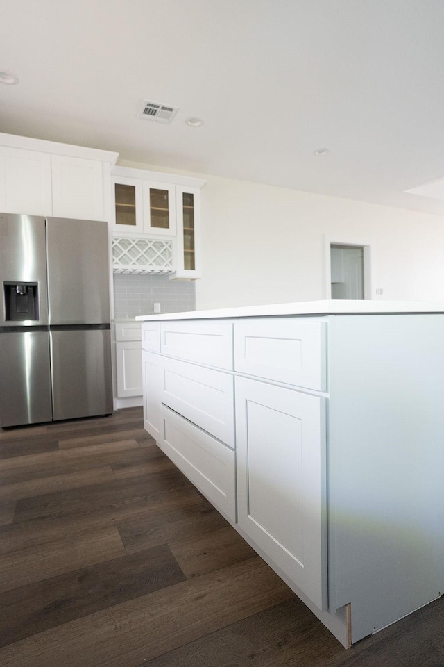 kitchen featuring white cabinetry, dark hardwood / wood-style floors, backsplash, and stainless steel fridge with ice dispenser