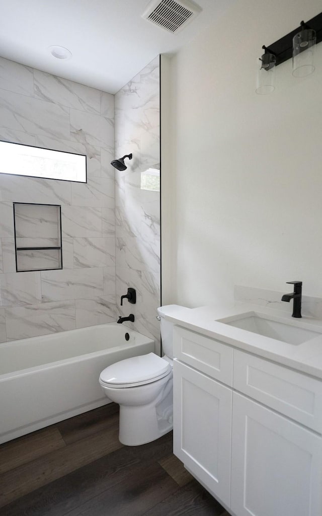 full bathroom with vanity, hardwood / wood-style flooring, toilet, and tiled shower / bath