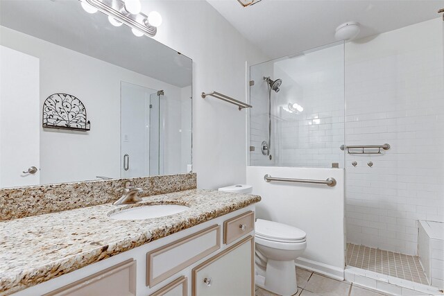 bathroom featuring vanity, tile patterned floors, toilet, and a tile shower