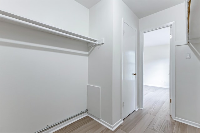 walk in closet with light hardwood / wood-style flooring