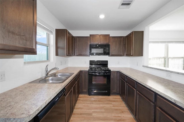 kitchen with sink, light hardwood / wood-style flooring, dark brown cabinetry, and black appliances