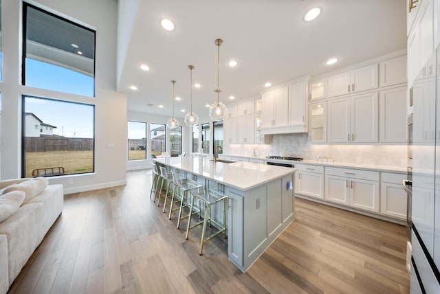 kitchen with a kitchen island with sink, pendant lighting, white cabinets, and a kitchen breakfast bar