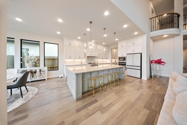 kitchen with white cabinetry, a spacious island, stainless steel appliances, and decorative light fixtures