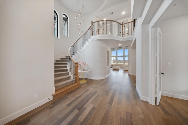 foyer with a high ceiling, hardwood / wood-style floors, and a notable chandelier