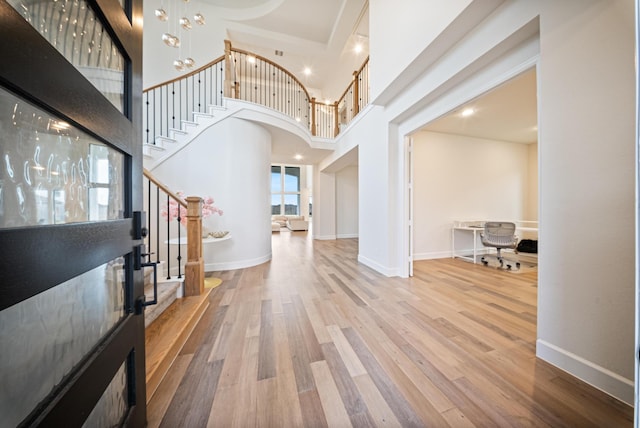 entrance foyer with hardwood / wood-style flooring, a high ceiling, and a notable chandelier