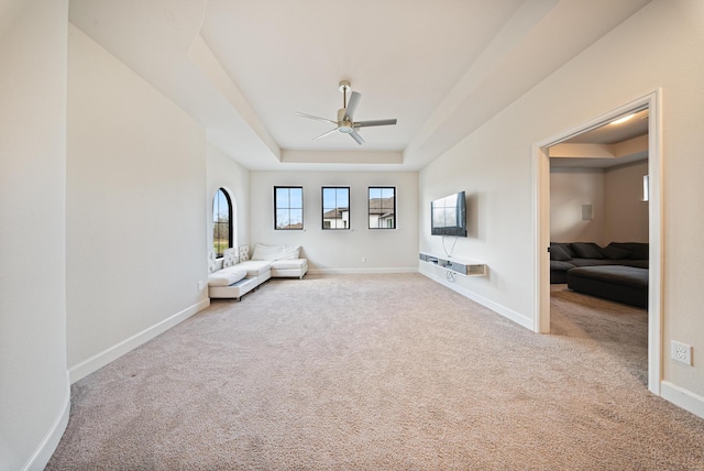 unfurnished room featuring light carpet, ceiling fan, and a tray ceiling