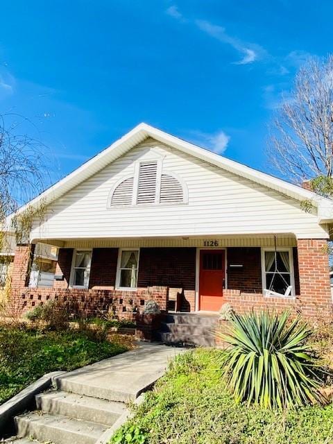 view of front of home featuring covered porch and brick siding