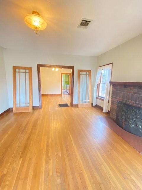 unfurnished living room with light hardwood / wood-style floors and a brick fireplace