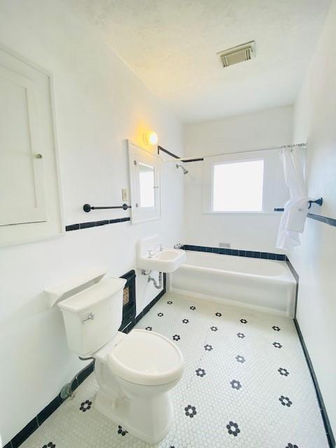 full bathroom featuring tile patterned flooring, shower / bath combo, sink, and toilet