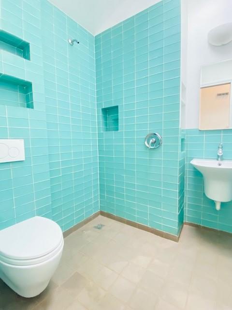 bathroom with tile walls and toilet