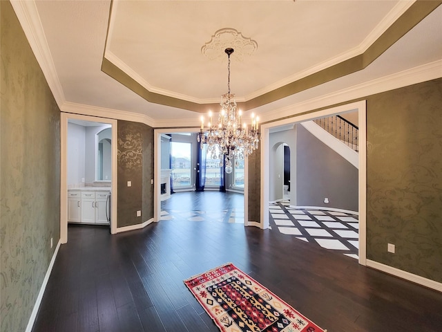 unfurnished dining area featuring an inviting chandelier, a tray ceiling, ornamental molding, and dark hardwood / wood-style floors