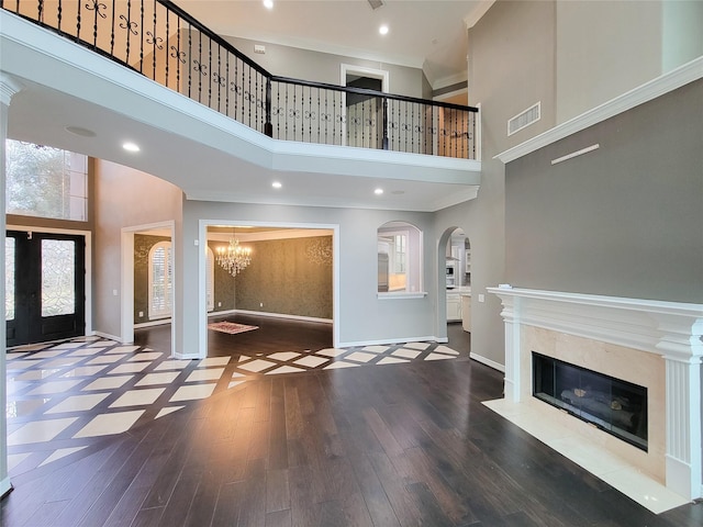 foyer entrance with wood-type flooring, a towering ceiling, a fireplace, and french doors