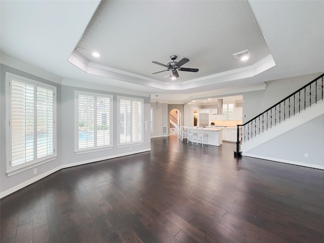 unfurnished living room with crown molding, a tray ceiling, dark hardwood / wood-style floors, and ceiling fan